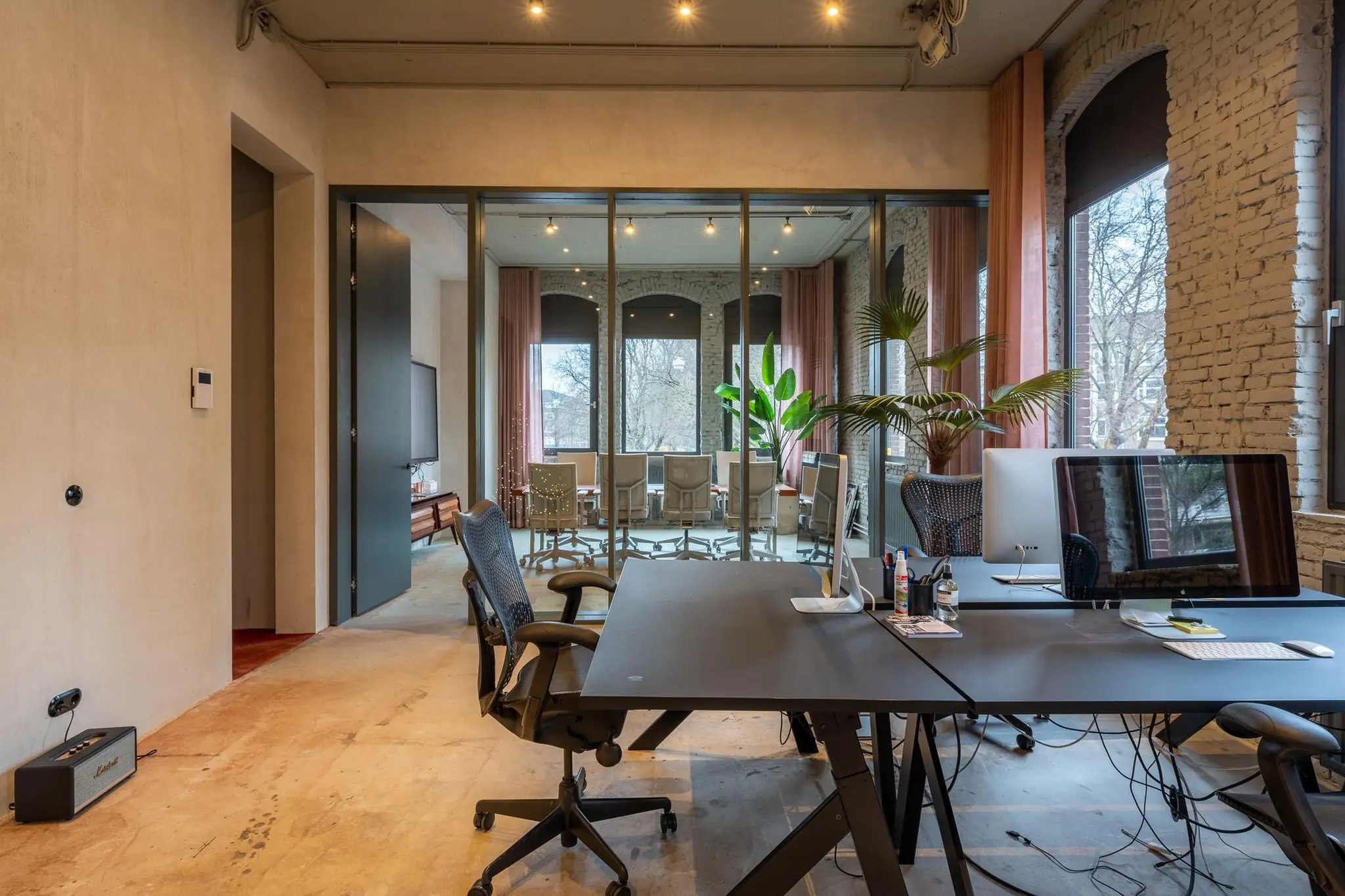 Modern kantoorinterieur aan de Admiraal de Ruijterweg met werkplekken, glazen vergaderruimte en grote ramen.